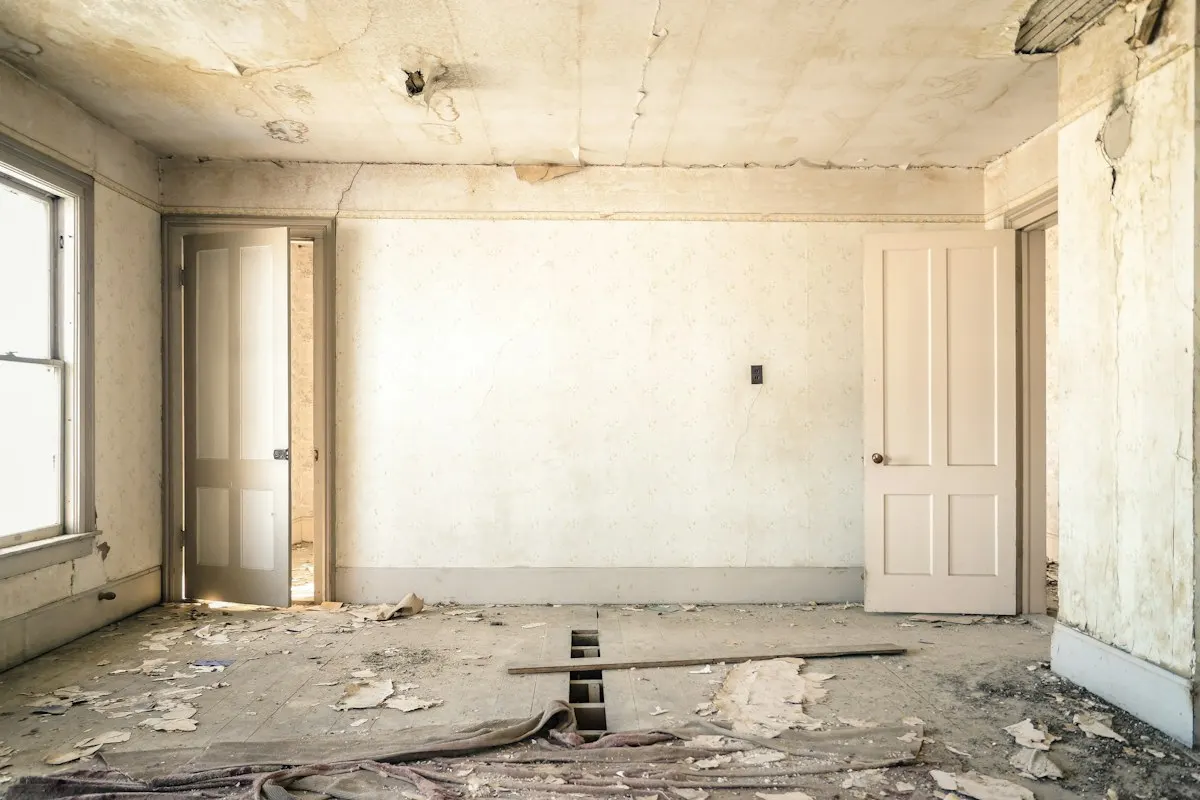 Empty room with stripped walls and a floor awaiting renovation