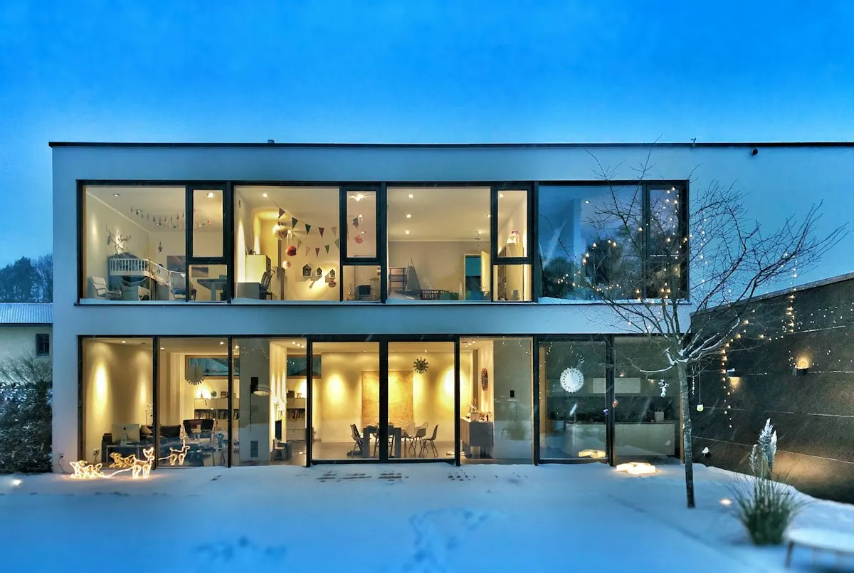 Glazed house exterior with interior lights at dusk
